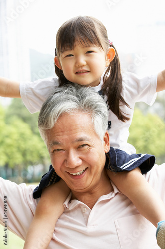 Chinese Grandfather Giving Granddaughter Ride On Shoulders