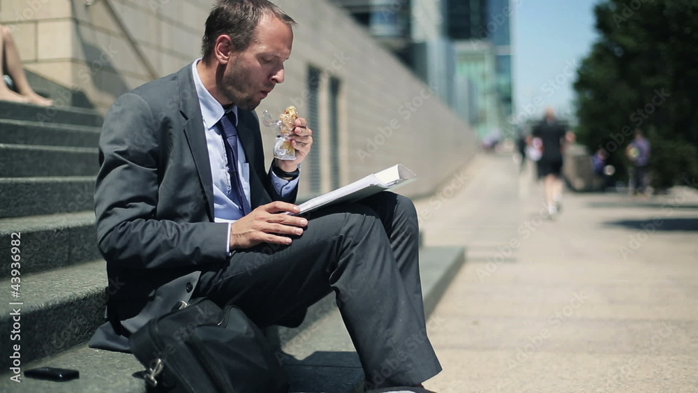 Businessman eating sandwich and reading documents Businessman eating sandwich and reading documents