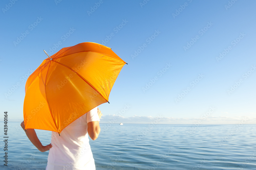 Woman with orange umbrella at ocean background