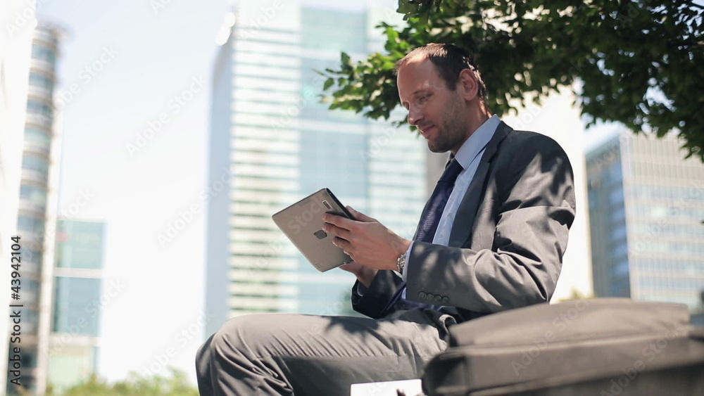 Businessman with tablet computer relaxing in the city Businessman with tablet computer relaxing in the city