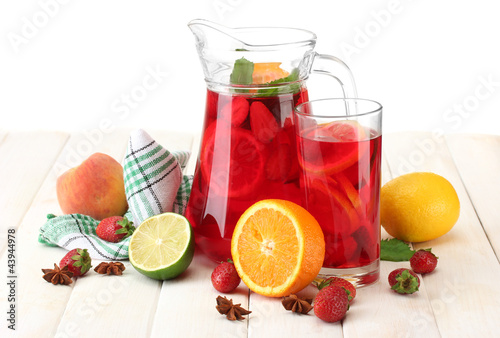 sangria in jar and glass with fruits, on white wooden table