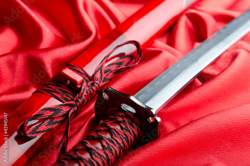 Japanese sword takana on red satin background photo