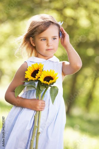 Young Girl Walking Through Summer Field Holding Sunflower