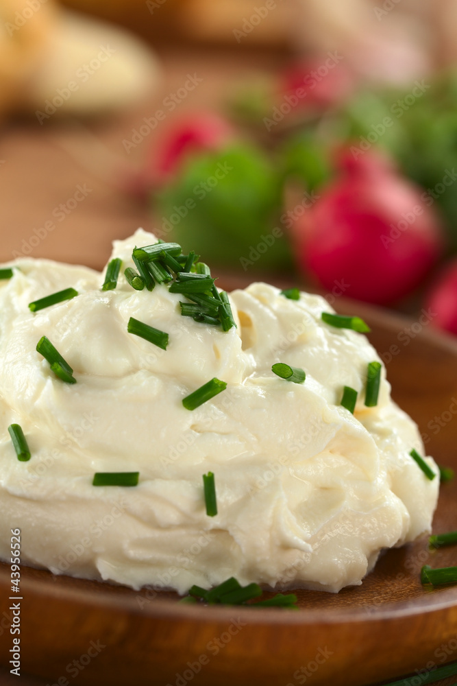 Fresh cream cheese spread on wooden plate with chives Fresh cream cheese spread on wooden plate with chives