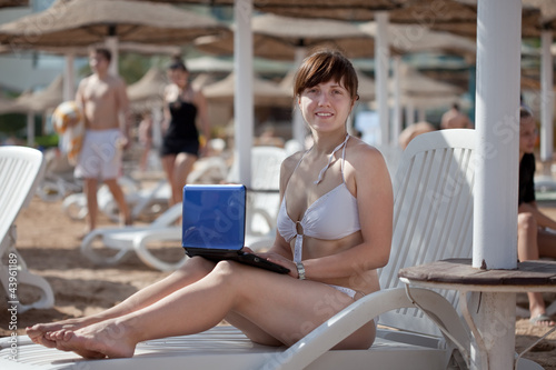 woman with laptop at resort beach