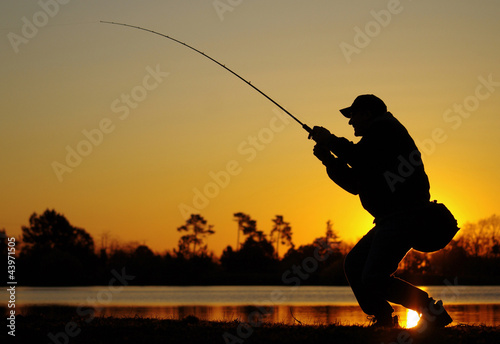 Pêcheur combattant un poisson au soleil couchant