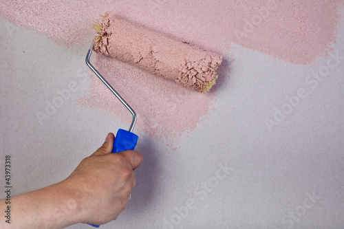 Picture of a hand painting the wall with roller