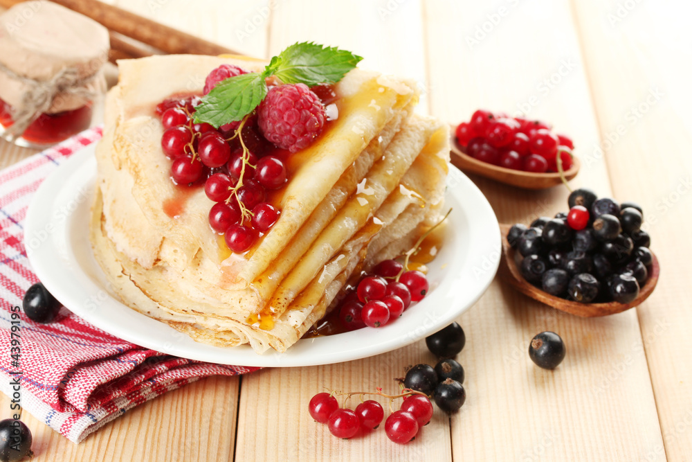 Delicious pancakes with berries, jam and honey on wooden table Delicious pancakes with berries, jam and honey on wooden table