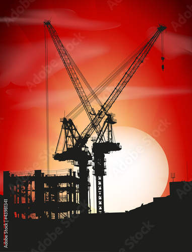 Silhouettes of two cranes on a sunset
