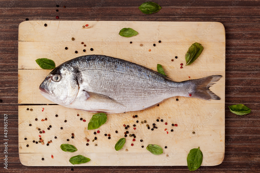 Fish on wooden board with herbs and spices. Fish on wooden board with herbs and spices.