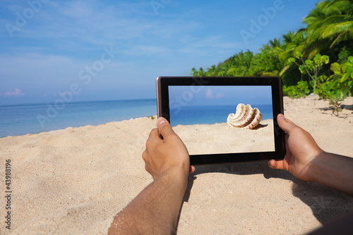 Fototapeta Naklejka Na Ścianę i Meble -  hands holding tablet pc on beach