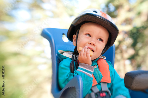 Little boy in bike child seat eating cracker