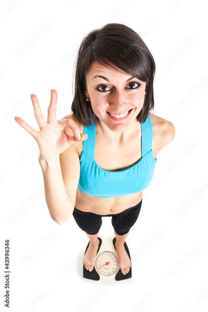 Fitness woman showing ok on a weighing scale Fitness woman showing ok on a weighing scale