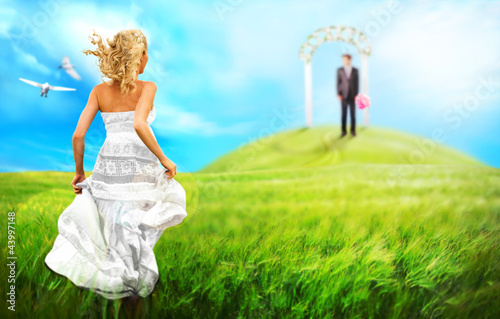 Young bride running to her groom to altar across the meadow. Wed photo