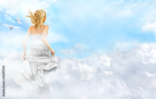 Young woman running across the clouds in the sky. Soul relaxatio