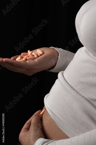 A pregnant woman holds some generic pills in her hand