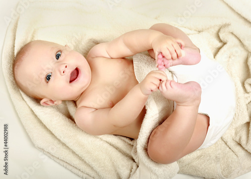 beautiful little boy lying on beige towel photo