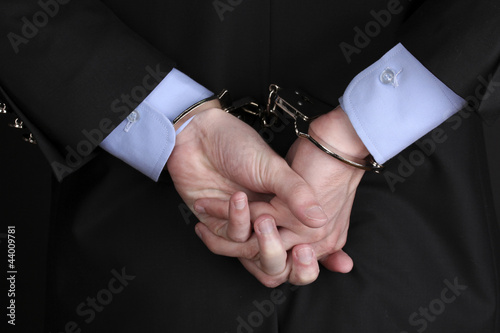 Businessman hands fettered with handcuffs