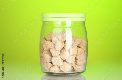 Jar with brown cane sugar lump on colorful background