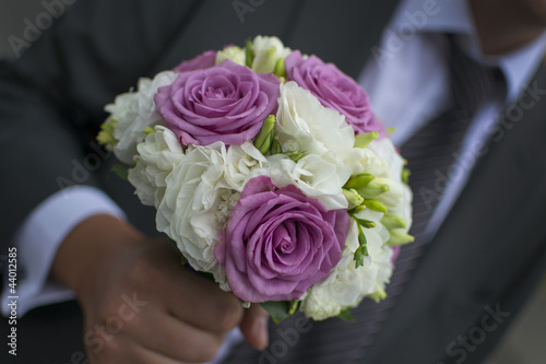 Close-up of a man's or groom's hand holding an elegant bouquet or bunch of flowers
