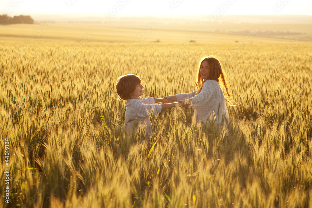 Happy mother and son are running through a wheat field Happy mother and son are running through a wheat field