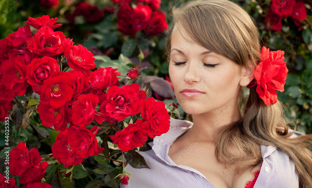 young woman in flower garden smelling red roses young woman in flower garden smelling red roses