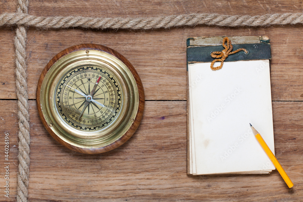 Compass, old notebook, pencil, rope on wood Compass, old notebook, pencil, rope on wood