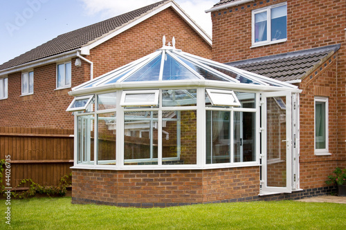 Fototapeta Conservatory with glass roof against a red brick house