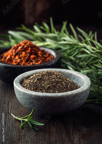 Black pepper in bowl  chili flakes and rosemary in background