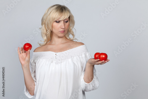 Беременная девушка держит красные помидоры в руках