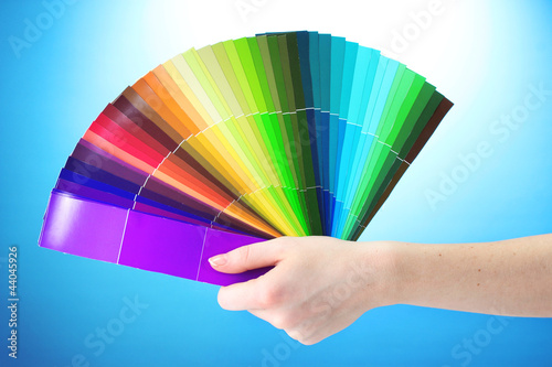hand holding bright palette of colors on blue background © Africa Studio