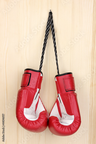 Red boxing gloves hanging on wooden background