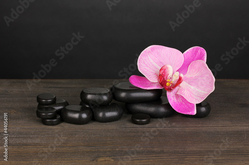 Spa stones with orchid flower on wooden table on grey