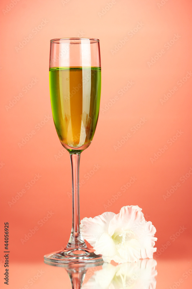 glass with cocktail and gladiolus bud on red background