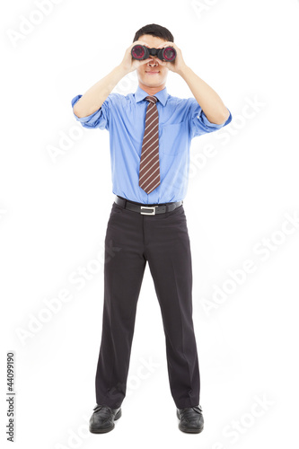 full length of businessman looks through binoculars and isolated