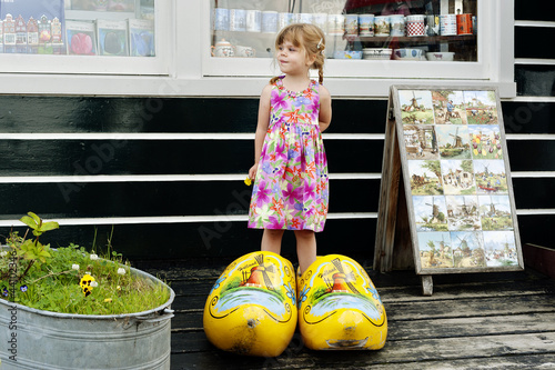 Little girl in giant wooden yellow clogs