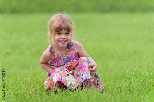 Happy little girl sitting in the grass