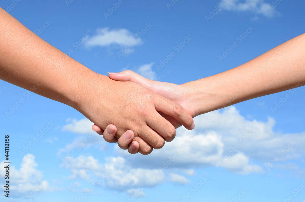 Hand shake between a man and a woman on blue sky background Hand shake between a man and a woman on blue sky background