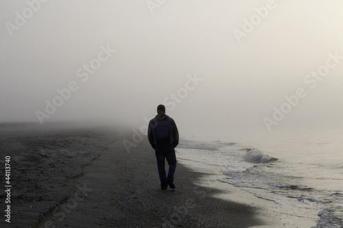 Lonely man walking on a beach photo
