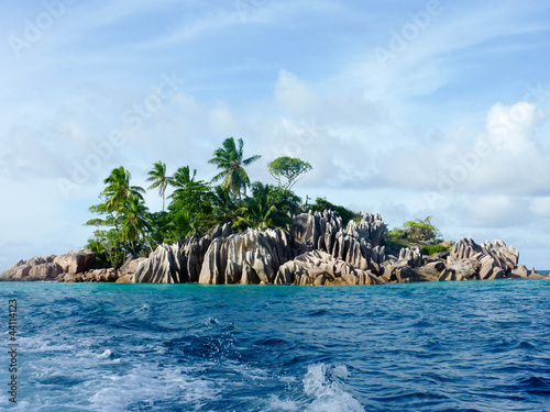 Roccky island with palm trees in ocean.