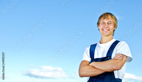 Smiling handyman in coveralls on sky background © M-Production