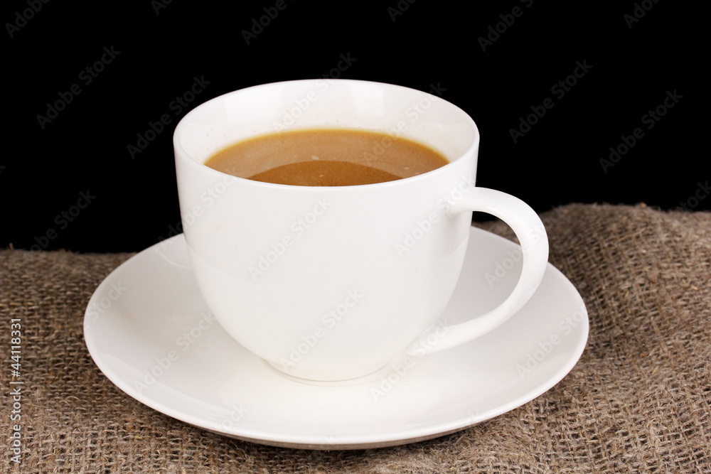 Cup of coffee on sacking on brown background