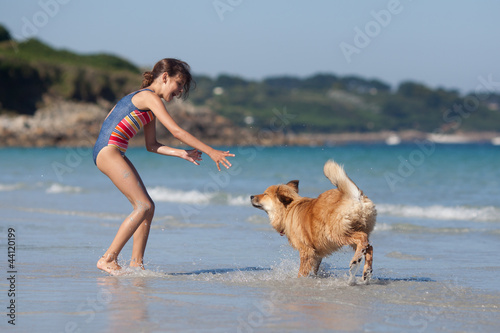 Mädchen und Elowelpe spielen am Strand