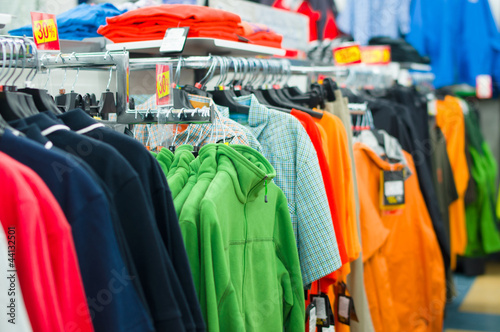 Variety of shirts, t-shirts and sweaters on stands in supermarke