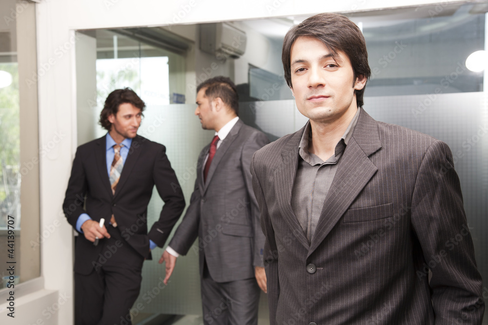 close up of asian businessman with colleagues in background close up of asian businessman with colleagues in background