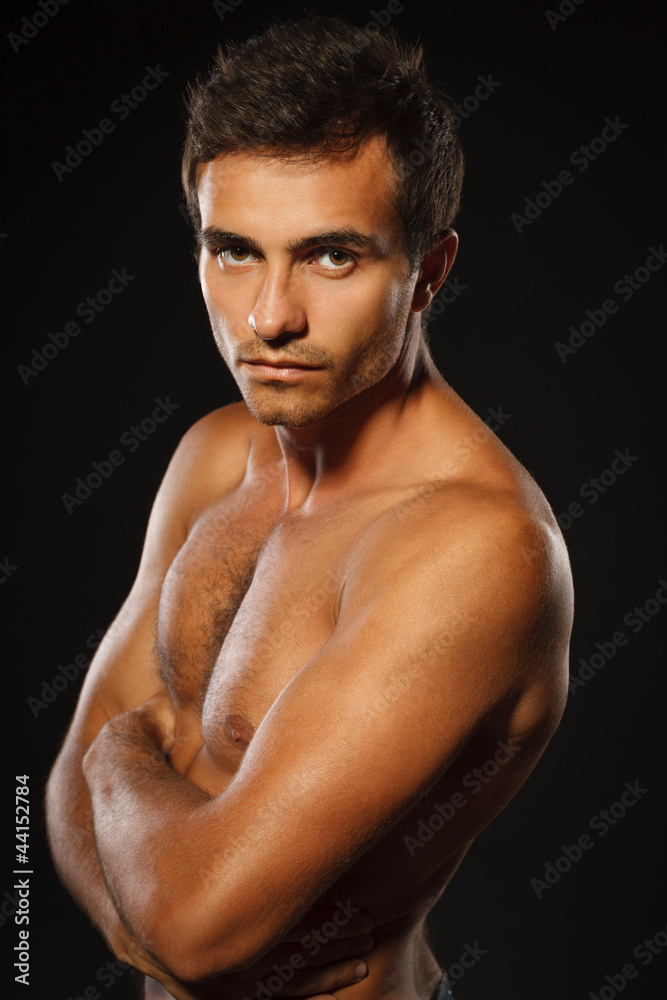 Young muscular male shirtless standing with folded hands