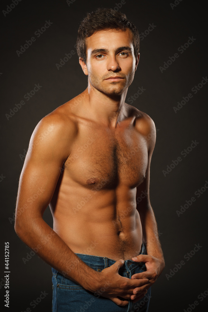 Fototapeta premium Young muscular male shirtless standing over dark background