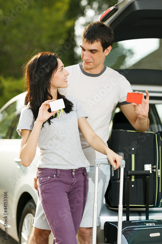 Couple standing near opened car boot with suitcases