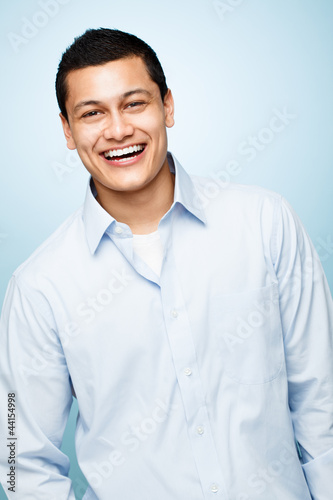 attractive confident young man smiling blue background © AILA_IMAGES