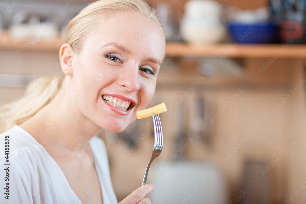 Woman tasting cooked macaroni in the kitchen, mac and cheese Woman tasting cooked macaroni in the kitchen, mac and cheese